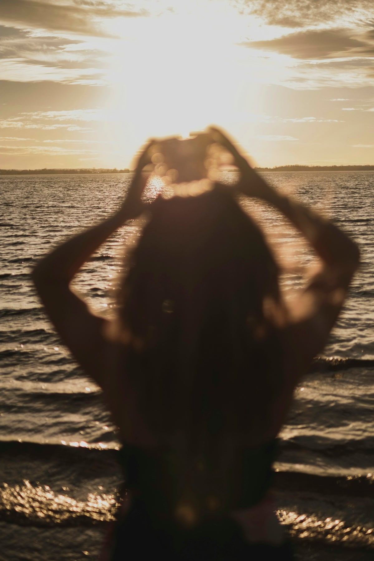 woman in black tank top standing on sea shore during sunset