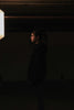 a woman standing in a dark room next to a light