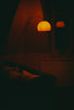 A floor lamp illuminates a dark room with a couch.