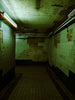 Abandoned, eerie hallway with peeling walls and dim lighting.
