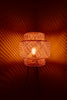 Woven bamboo lamp casting patterned light on wall