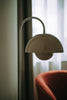 A modern floor lamp beside an orange armchair.