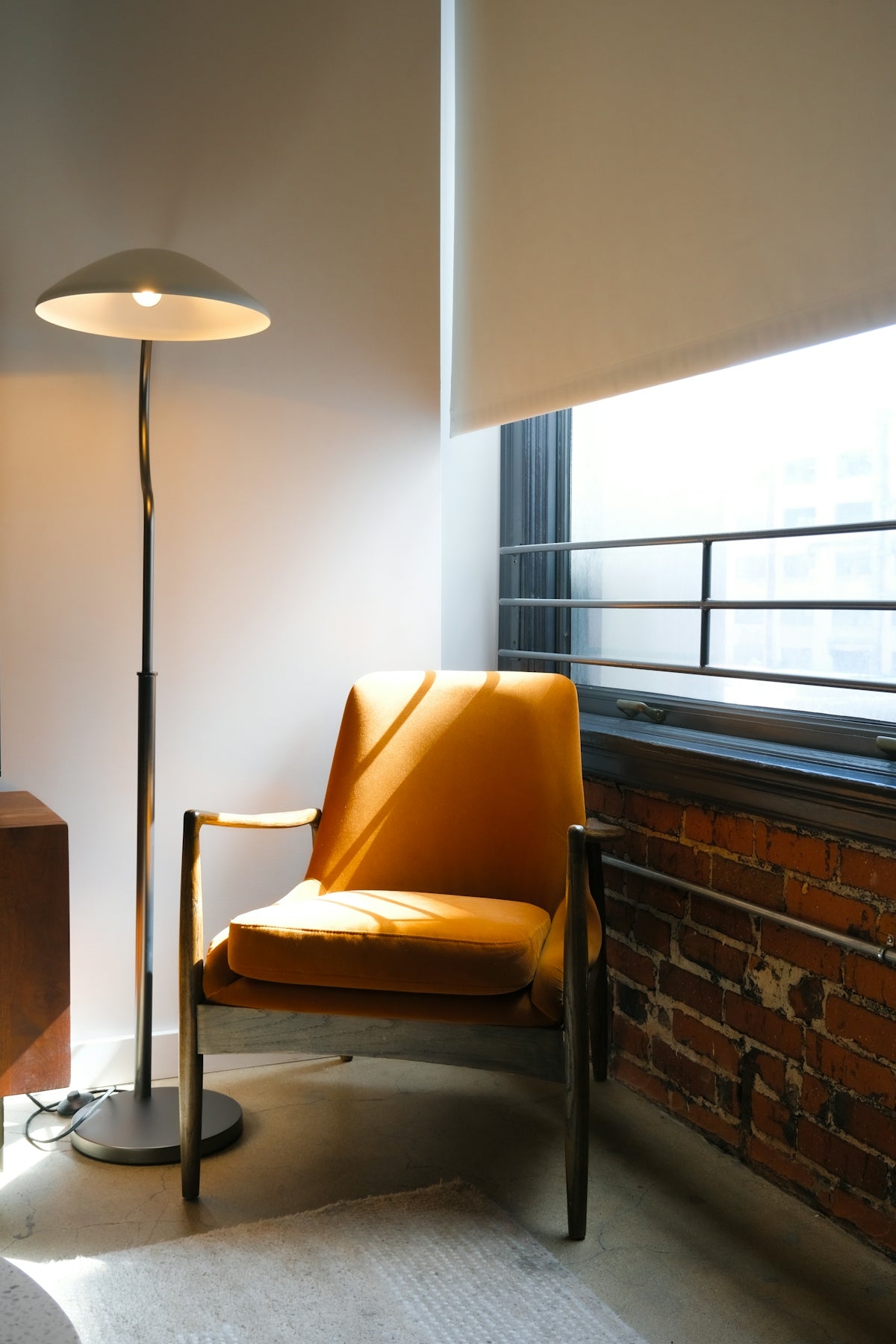 Orange armchair next to a floor lamp near window.