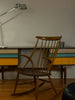 Wooden rocking chair in front of a colorful desk.