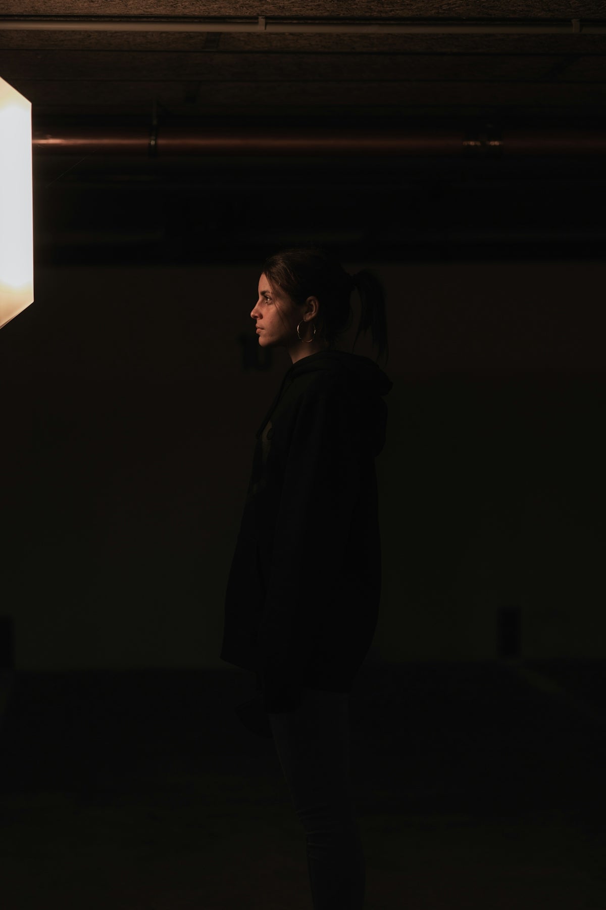 a woman standing in a dark room next to a light