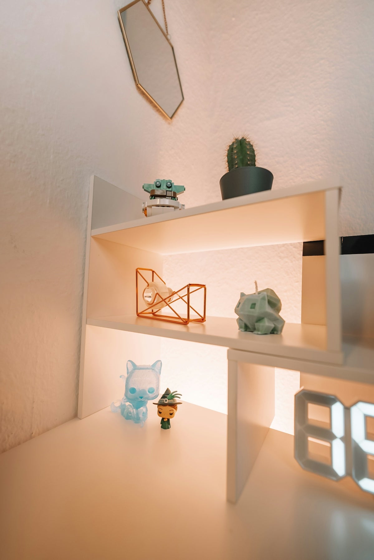 a white shelf with a clock and a cat figurine on it