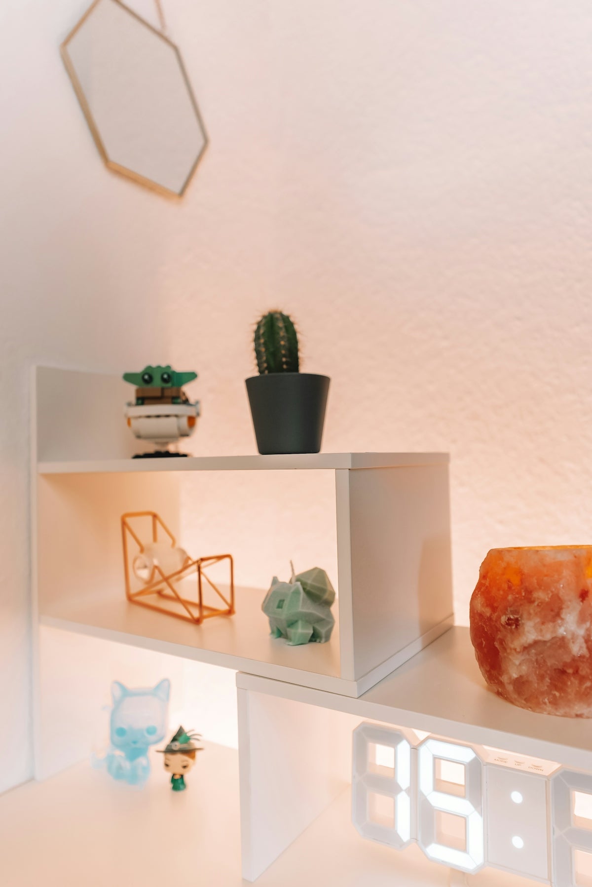 a white shelf with a clock and a cactus