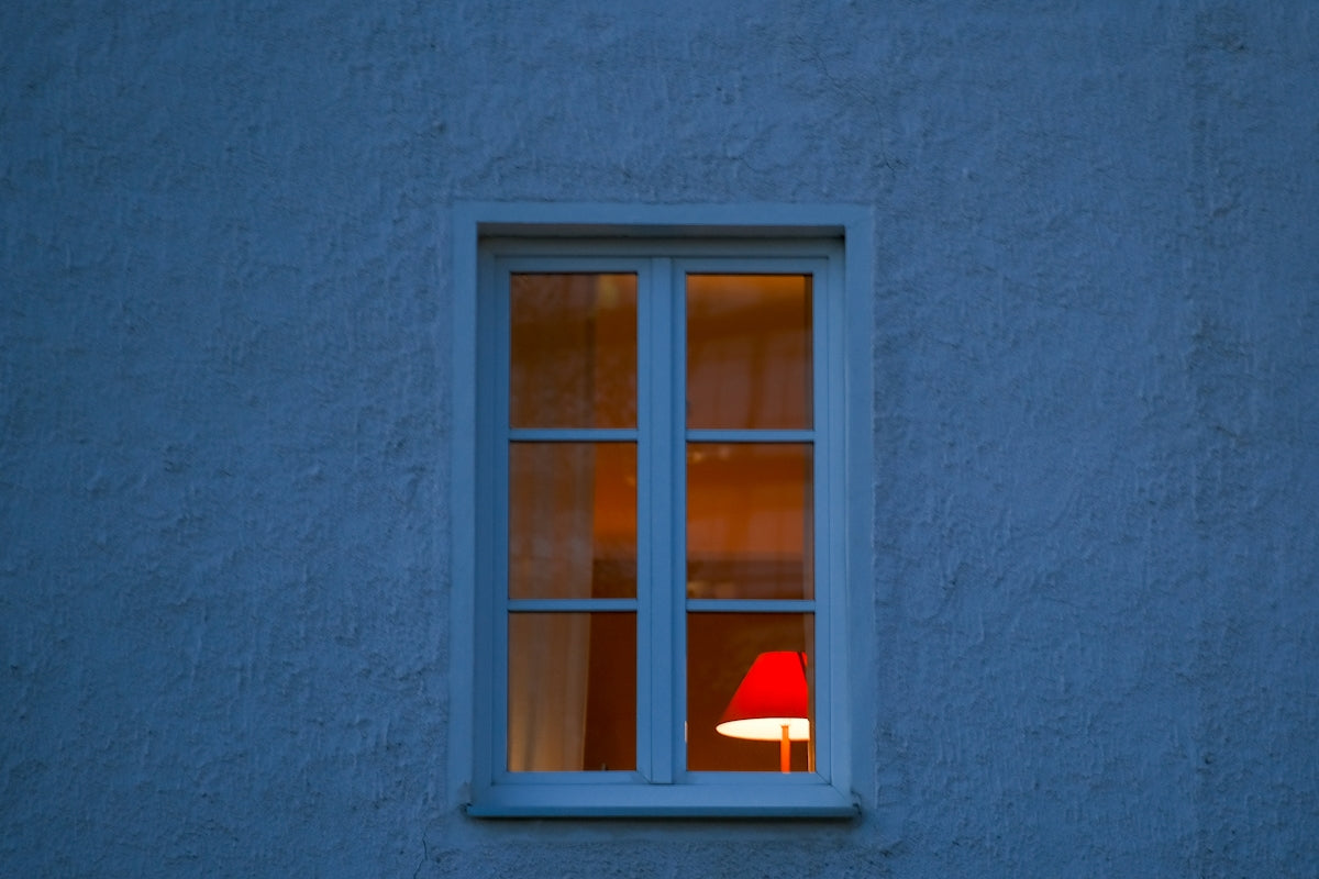 a red lamp sitting in a window next to a blue wall
