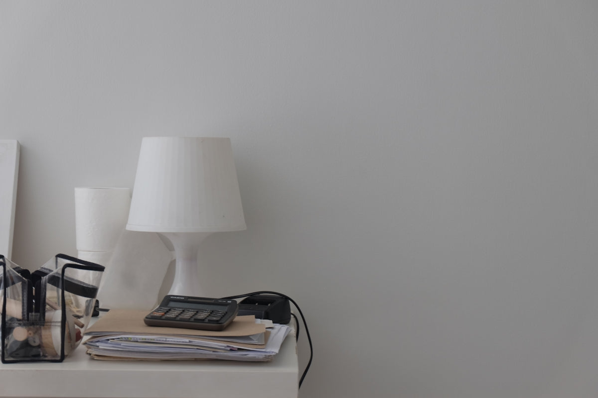 a white table topped with a lamp and a phone