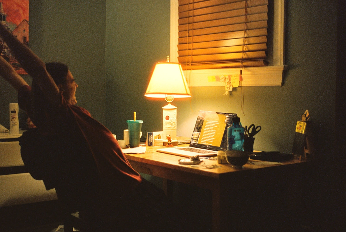 a woman sitting at a desk in front of a lamp