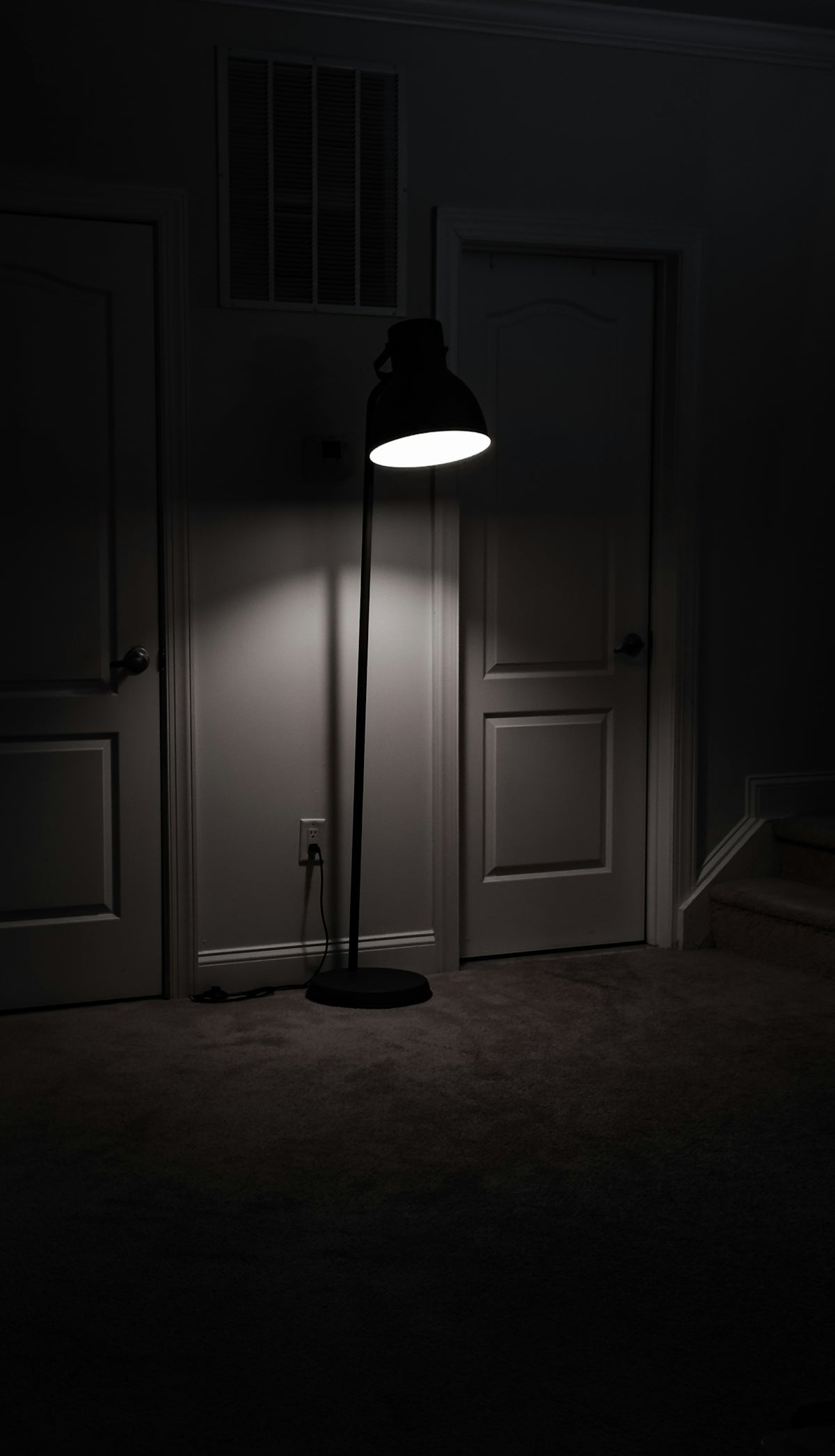a dark room with a lamp on the floor