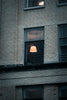 a brick building with a lamp in the window
