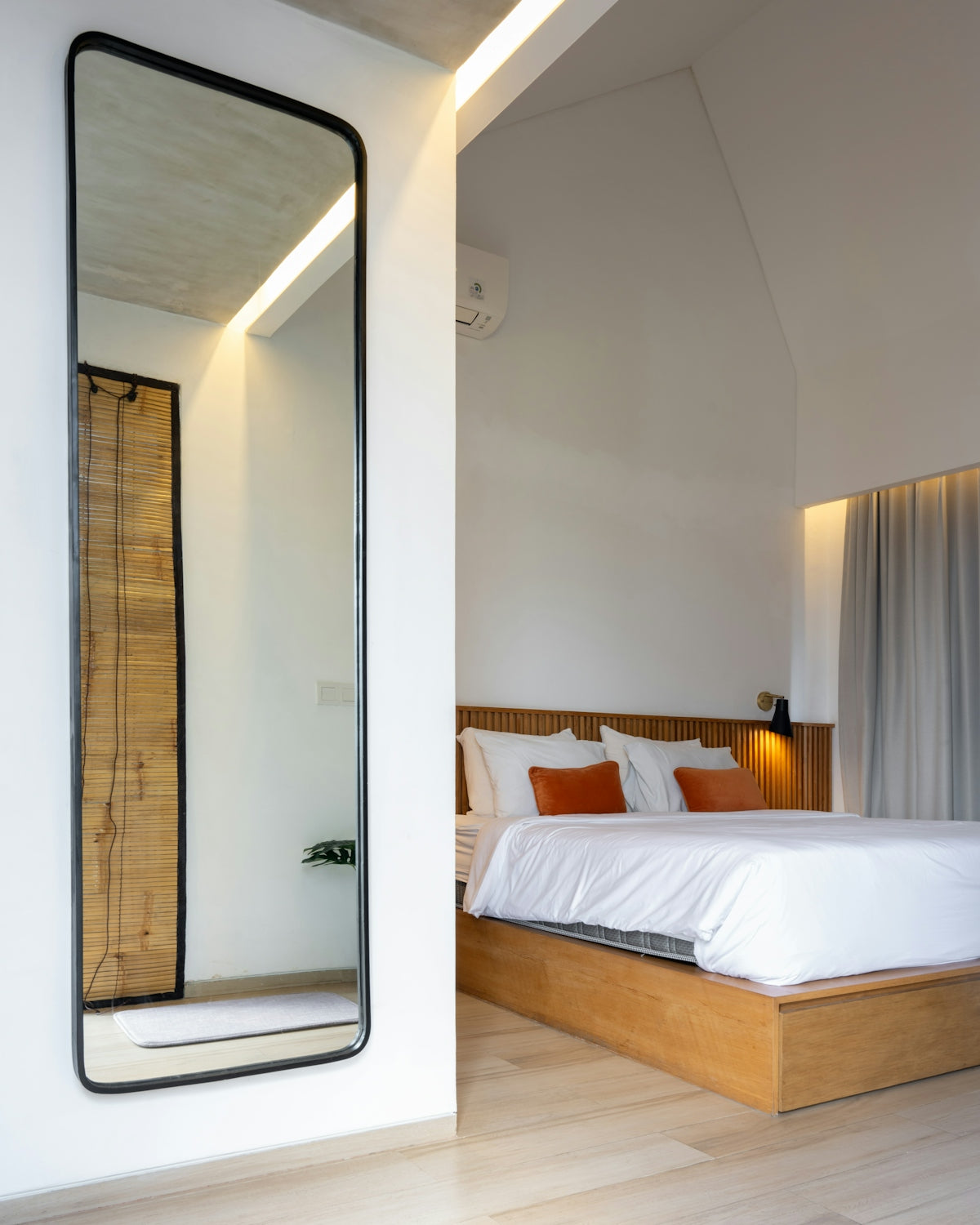 A bedroom with a bed and a large mirror