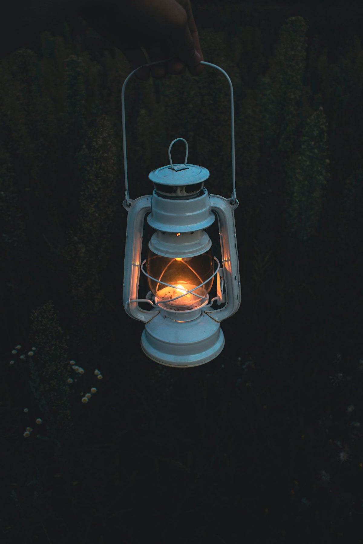 A person holding a lit lantern in the dark