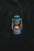 A person holding a lit lantern in the dark