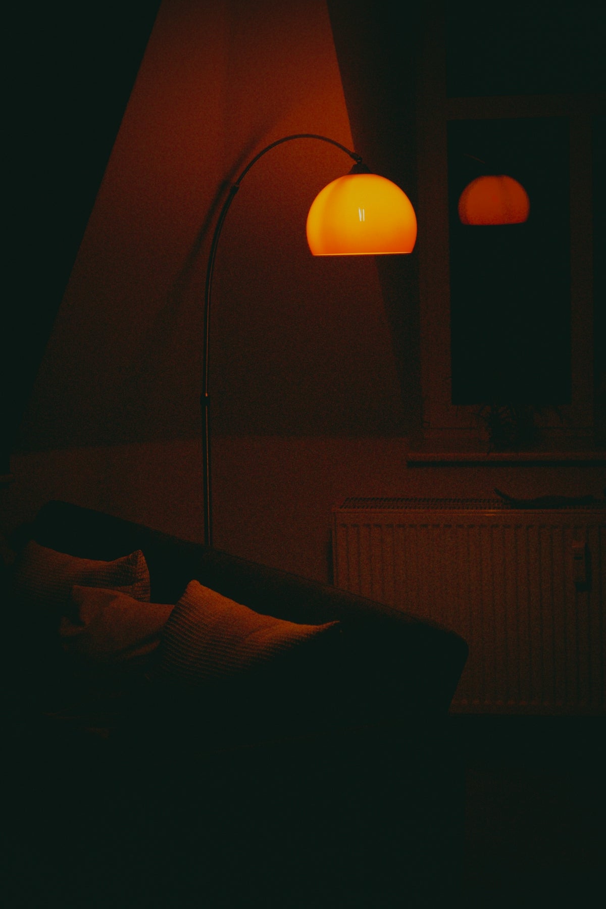 A floor lamp illuminates a dark room with a couch.