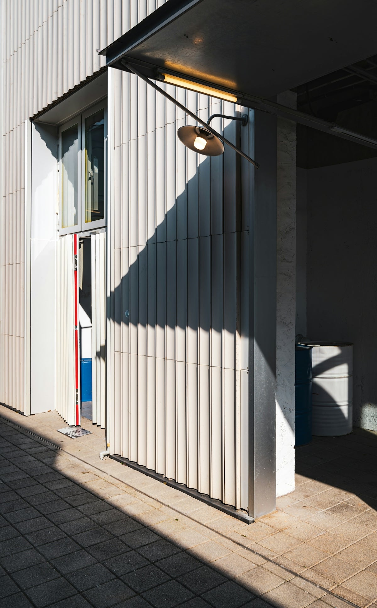 A white building with a light hanging from it's side