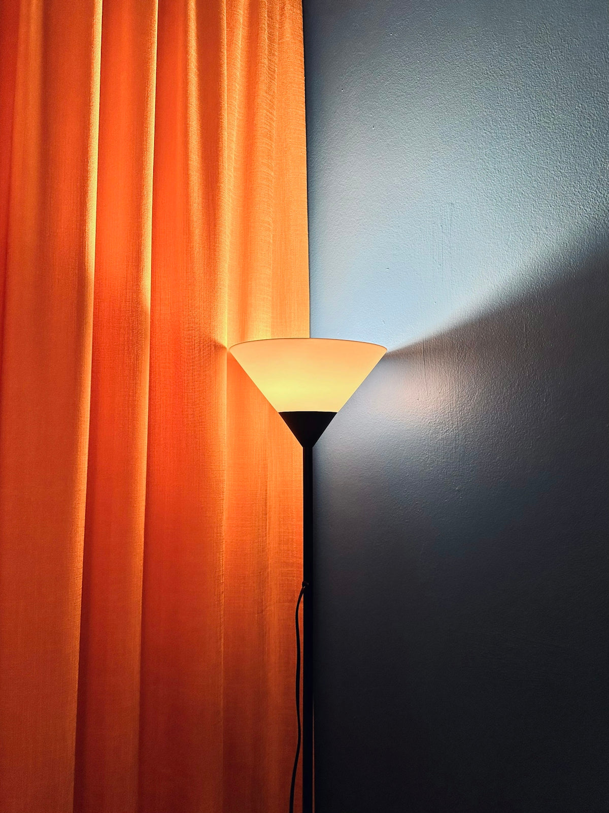 A lit lamp casts a shadow on the wall.