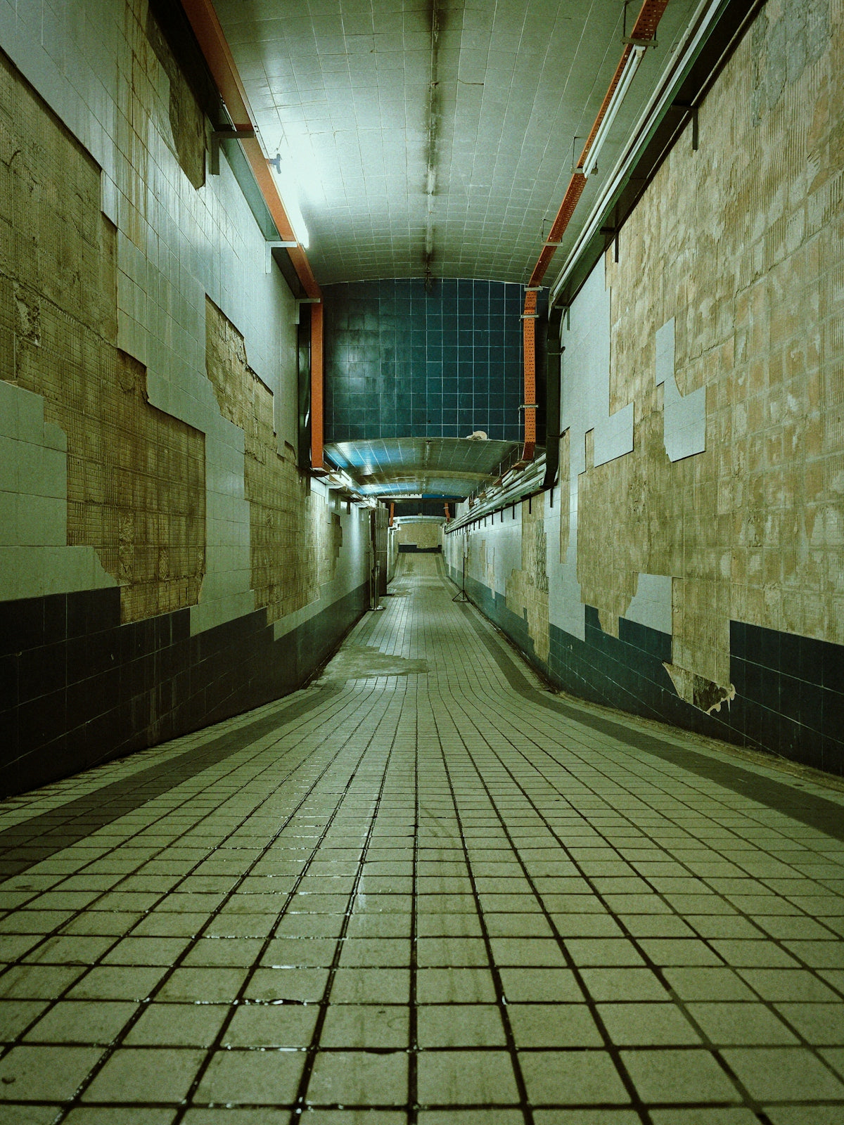 An eerie, tiled hallway with peeling walls.