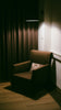 A lit armchair is sitting in a darkened corner.