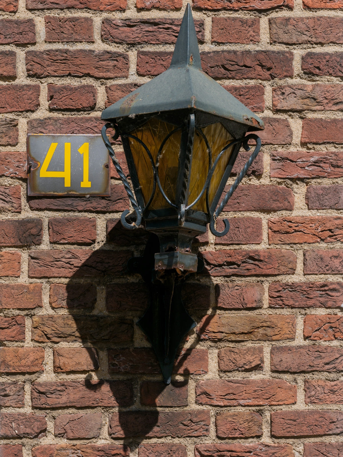 A decorative lamp is mounted on a brick wall.