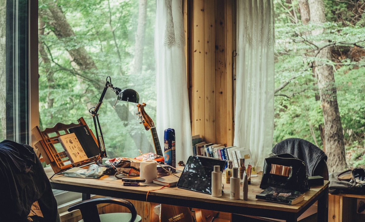 A cluttered desk in a room with a large window.