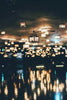 Many hanging lanterns illuminate a dark room with reflections.