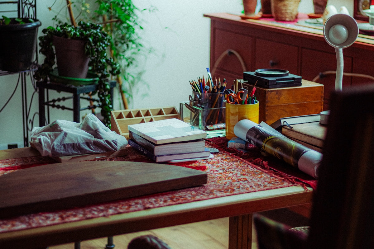 Art supplies and plants on a wooden desk.