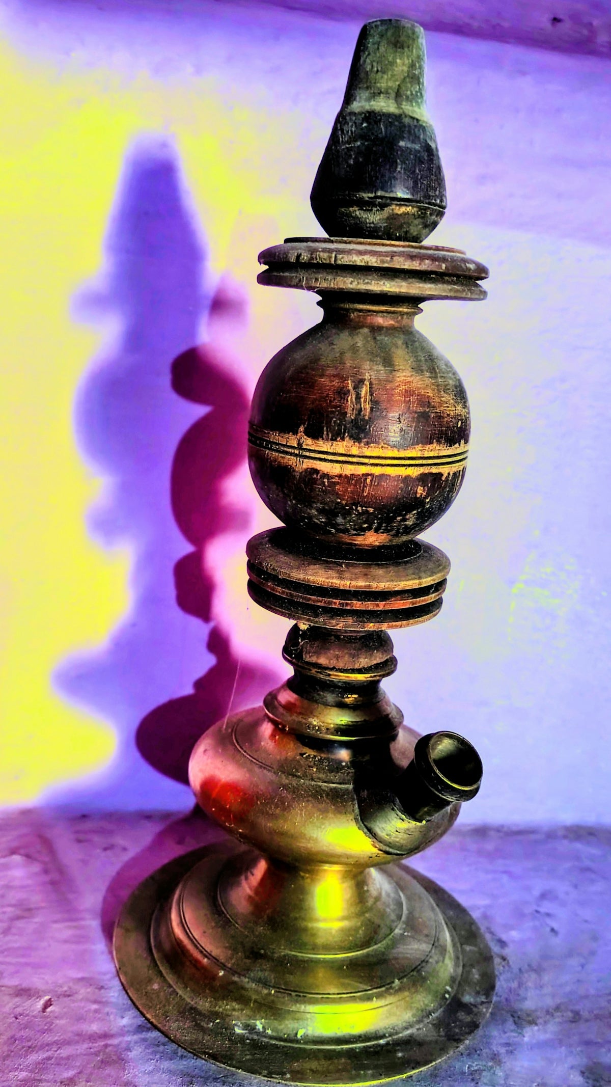 An antique brass and wood oil lamp with a shadow.