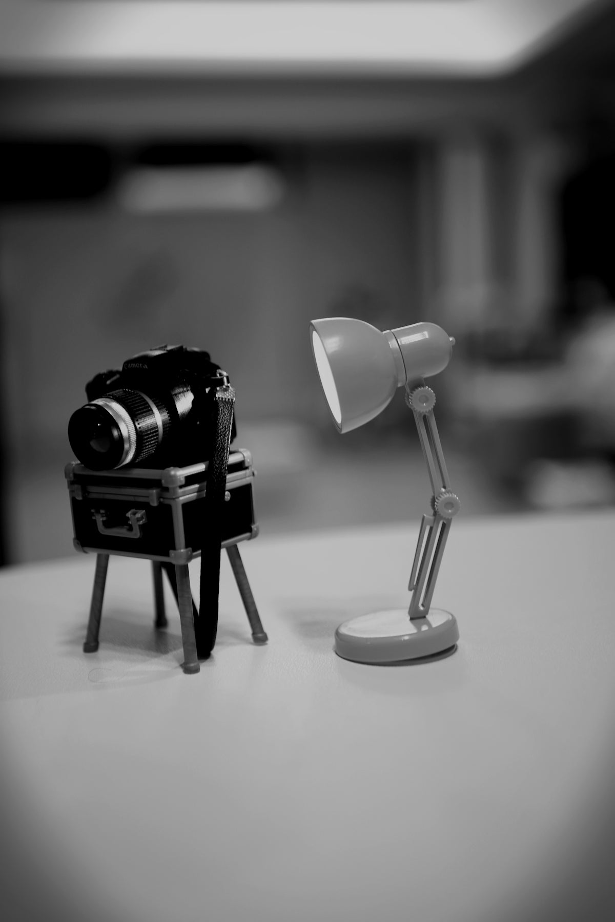 Miniature camera on tripod next to desk lamp