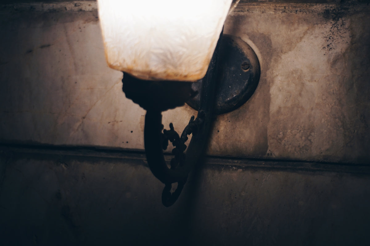 Close-up of a vintage wall sconce with a lit bulb.
