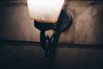Close-up of a vintage wall sconce with a lit bulb.