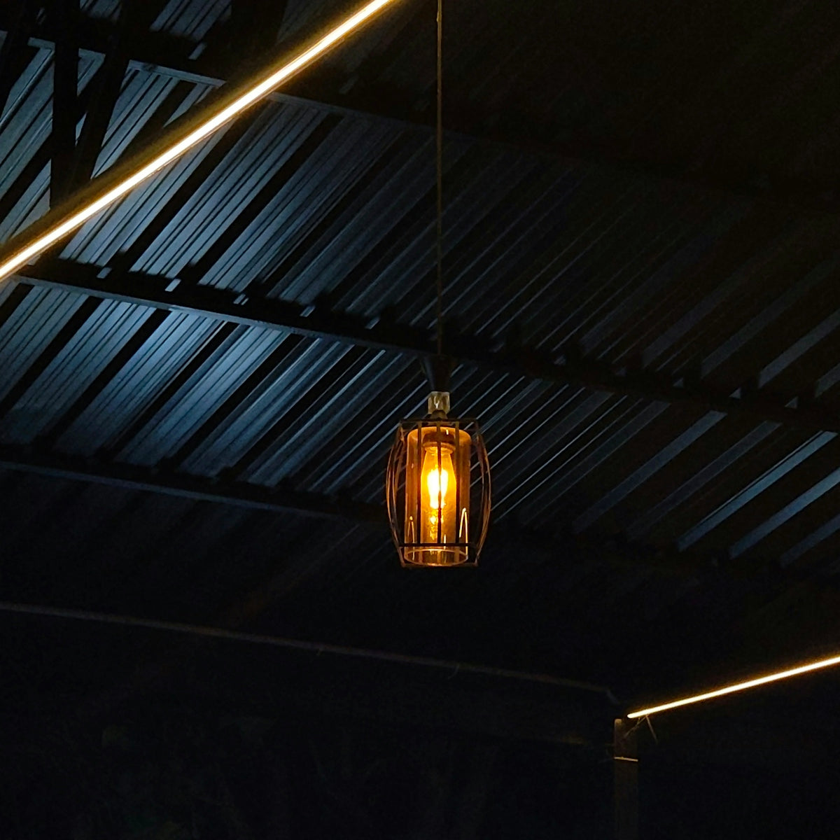 A single hanging light fixture illuminates a dark ceiling.