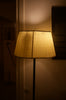 A lit floor lamp with a pleated shade.