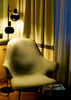 A modern armchair next to a floor lamp and curtains.