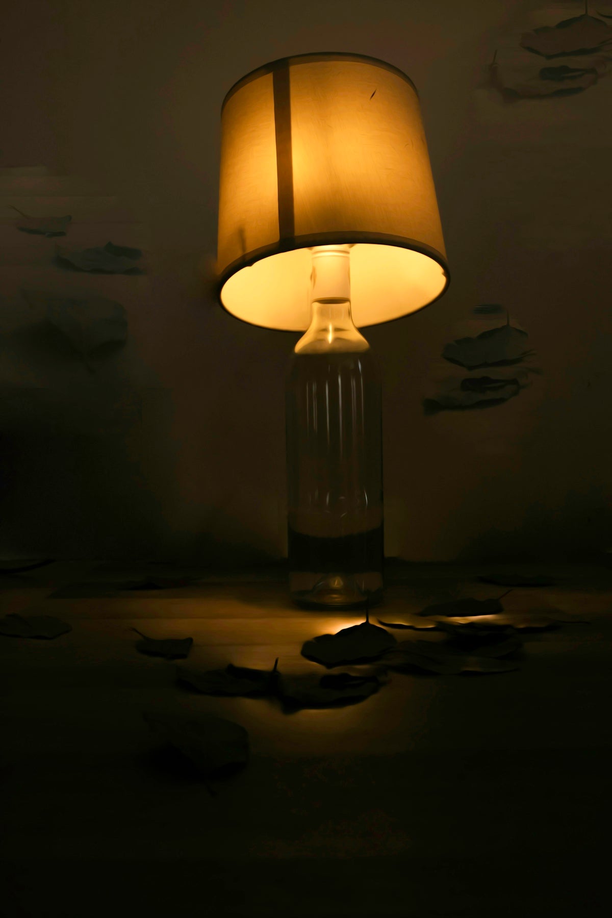 A lamp with a glass bottle base illuminates fallen leaves.