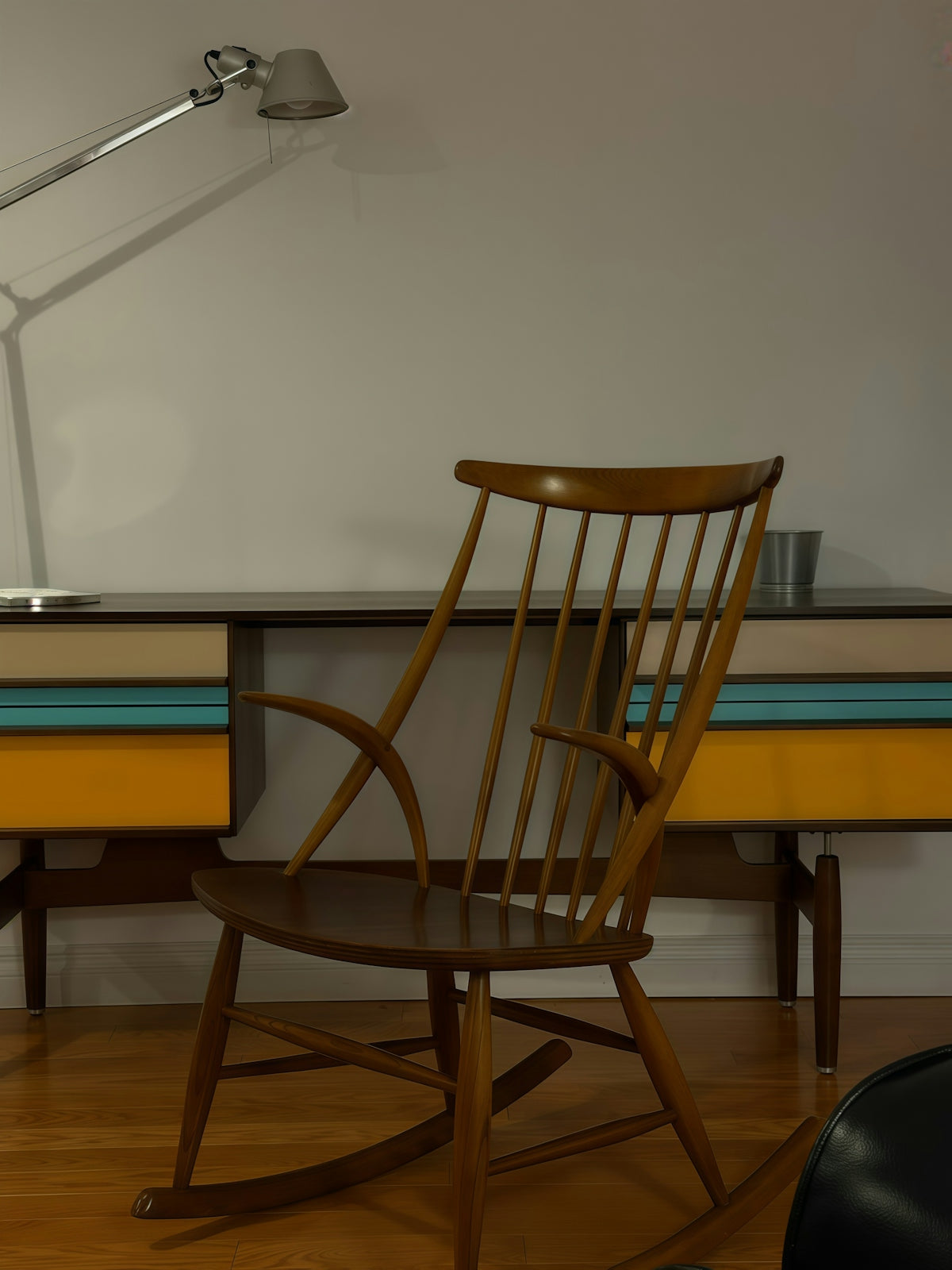 Wooden rocking chair in front of a colorful desk.