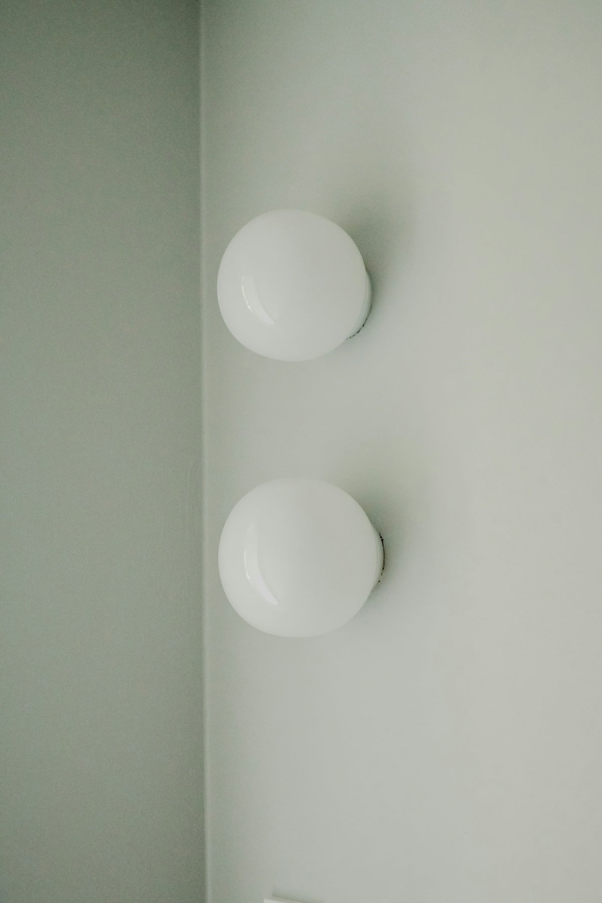 Two white globe lights on a pale wall