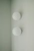 Two white globe lights on a pale wall