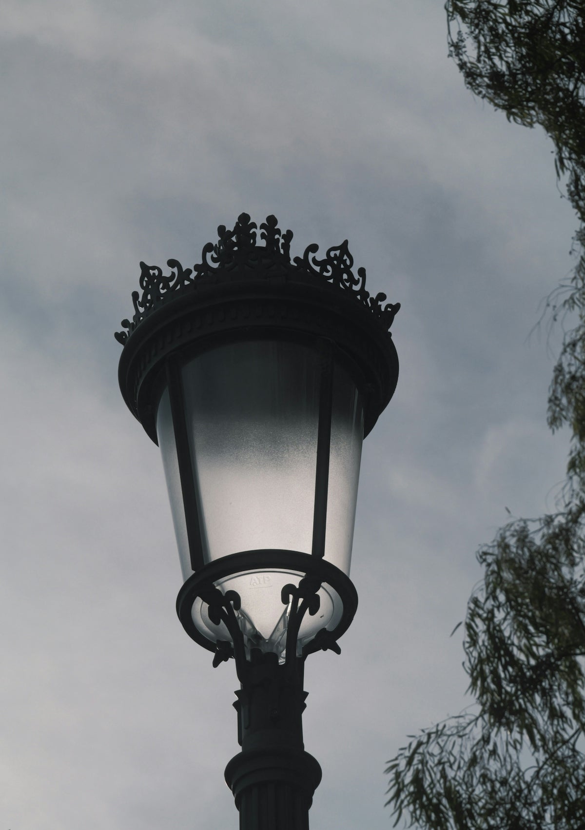An ornate vintage street lamp against a cloudy sky.