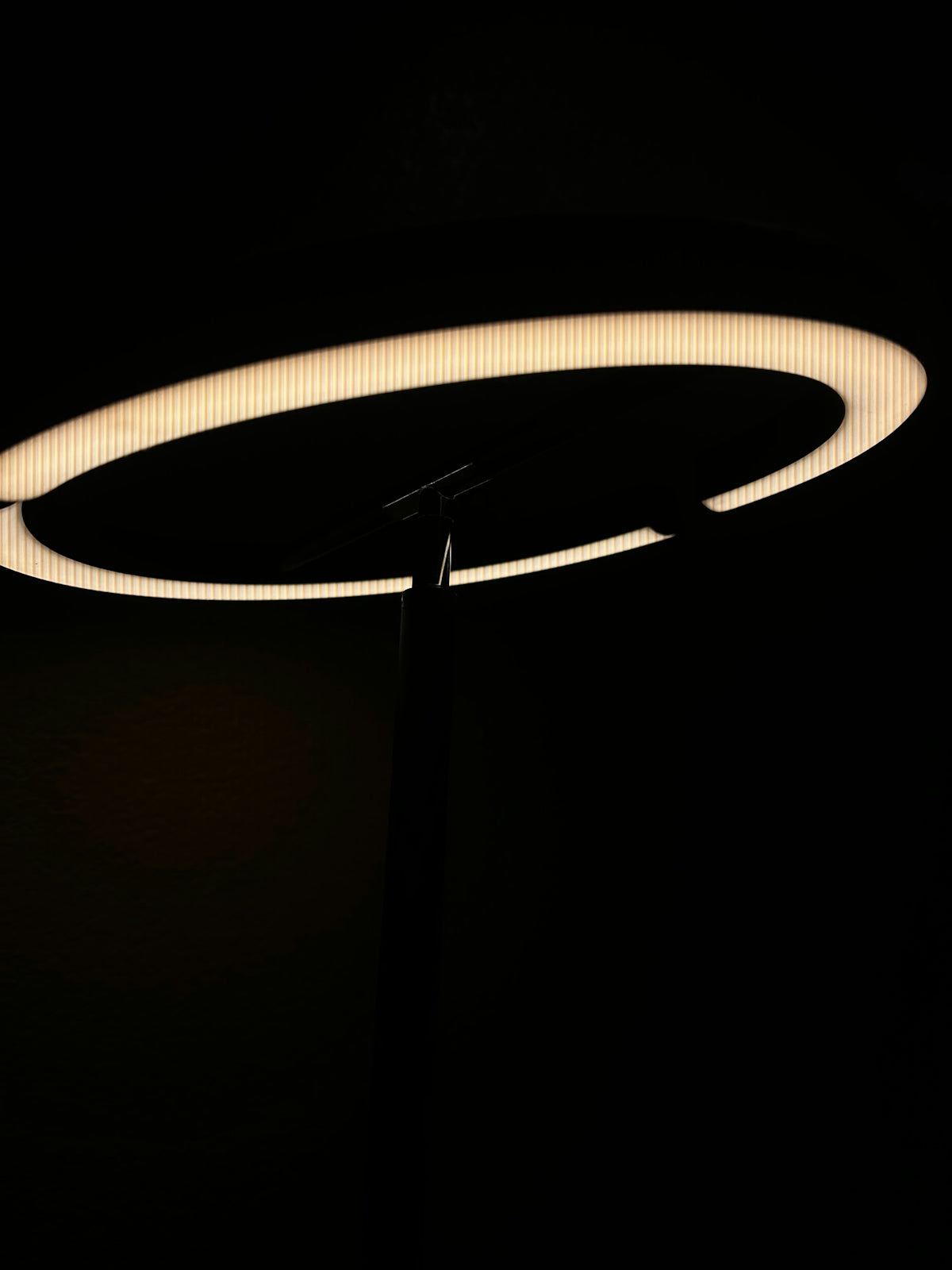 A modern ring-shaped light fixture against darkness