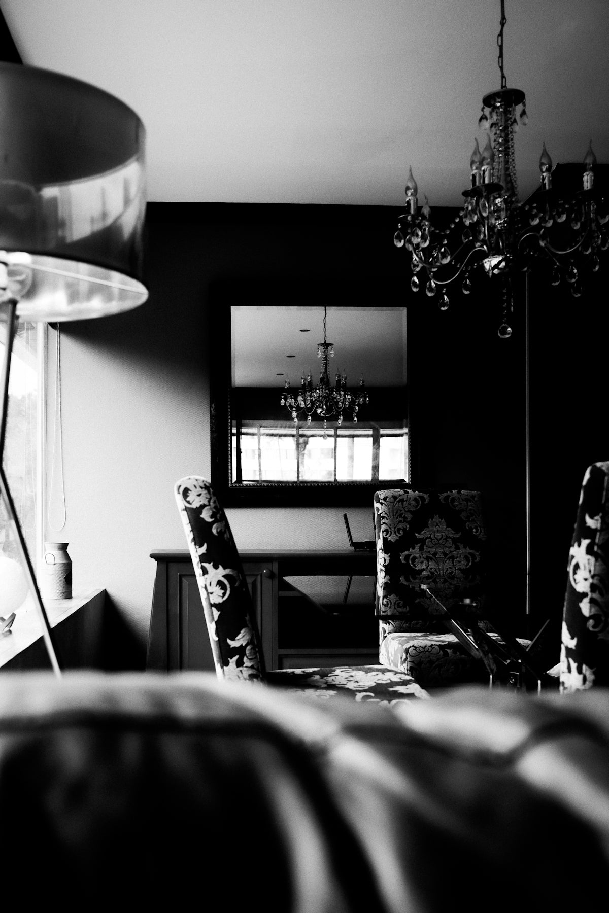 Ornate chandelier reflected in a mirror above a dining table.