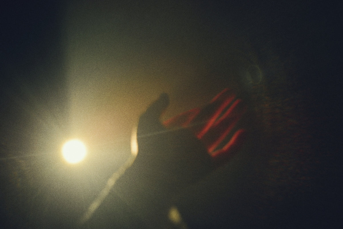 A hand reaching towards a bright light source.