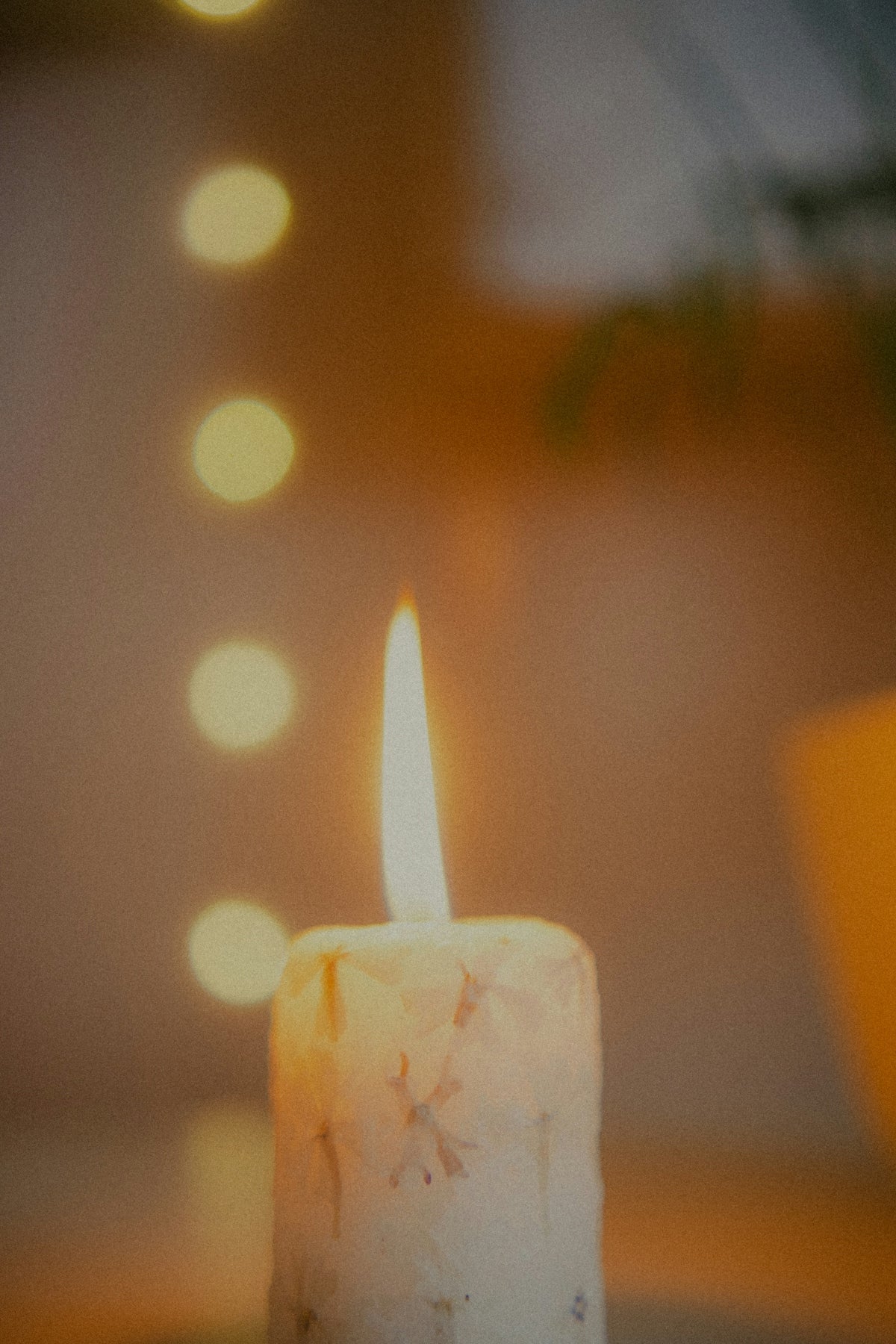 A lit candle with bokeh lights in the background.
