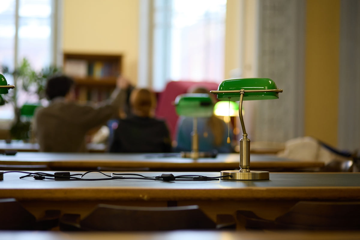 Green desk lamps on tables in a library