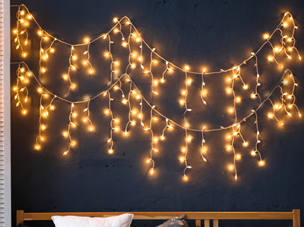 300 LED indoor outdoor lighting in warm white strands creating a cozy ambiance above a bed